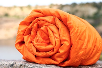 Rolled sleeping bag outdoors on sunny day, closeup