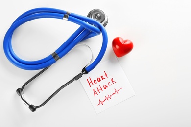 Photo of Stethoscope, note with phrase "HEART ATTACK" and small red heart on light background