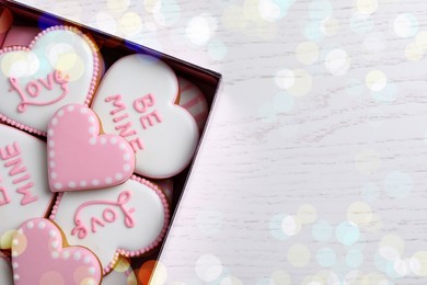 Photo of Delicious heart shaped cookies in box on white wooden table, top view. Space for text