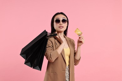 Photo of Beautiful woman with shopping bags and credit card on pink background