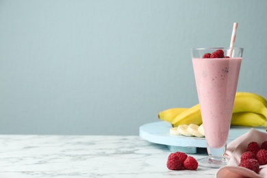 Image of Yummy raspberry smoothie in glass on white marble table, space for text 