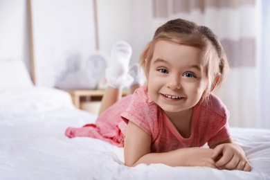 Photo of Cute little girl on bed at home