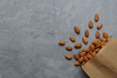 Photo of Paper bag with delicious almonds on grey table, top view. Space for text