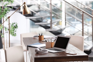 Photo of Workplace with laptop and headphones in modern office