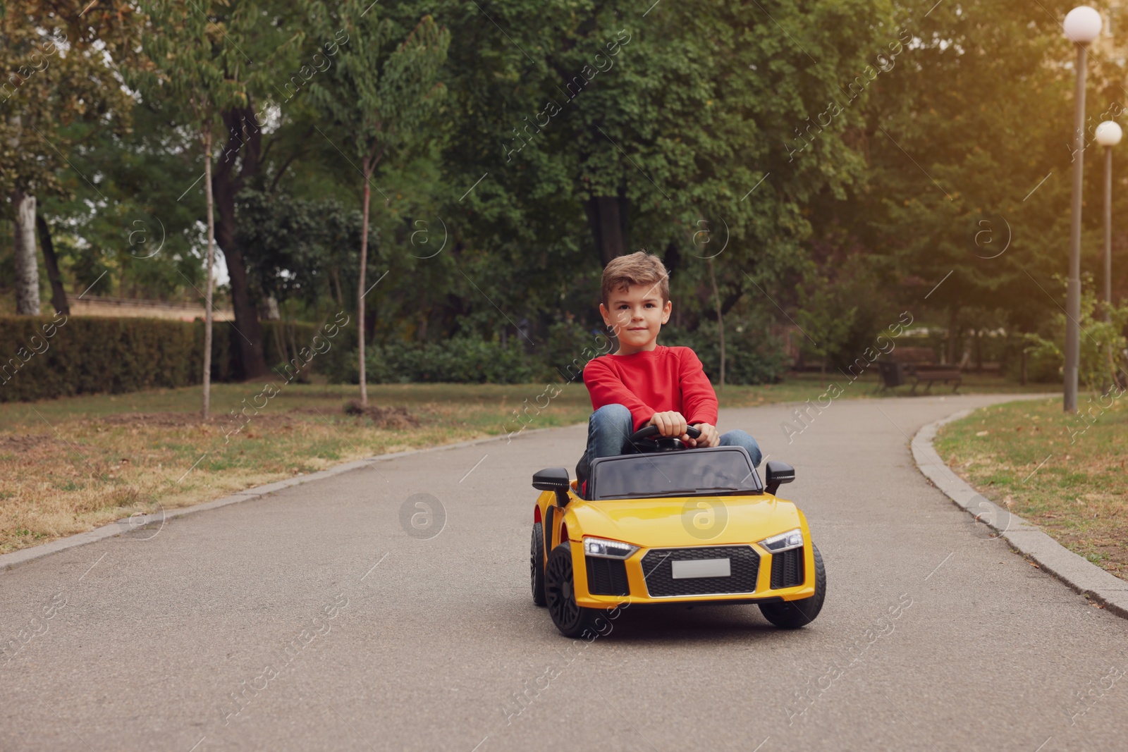 Photo of Cute little boy driving children's car outdoors. Space for text