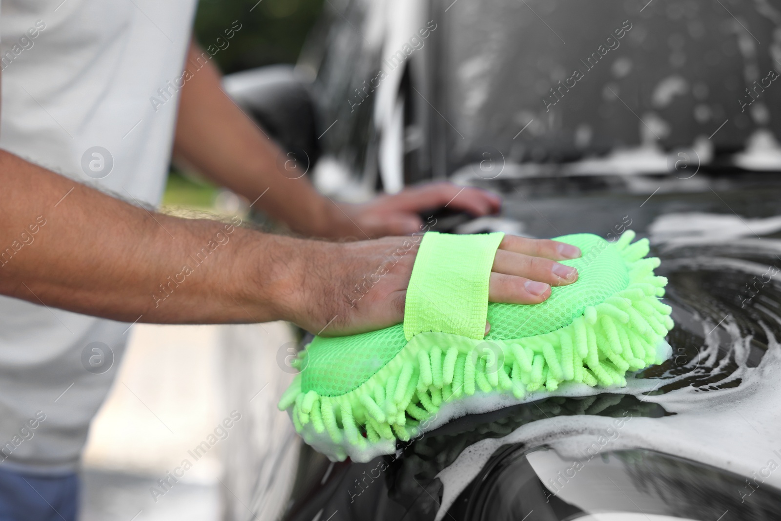 Photo of Man washing car with sponge outdoors, closeup