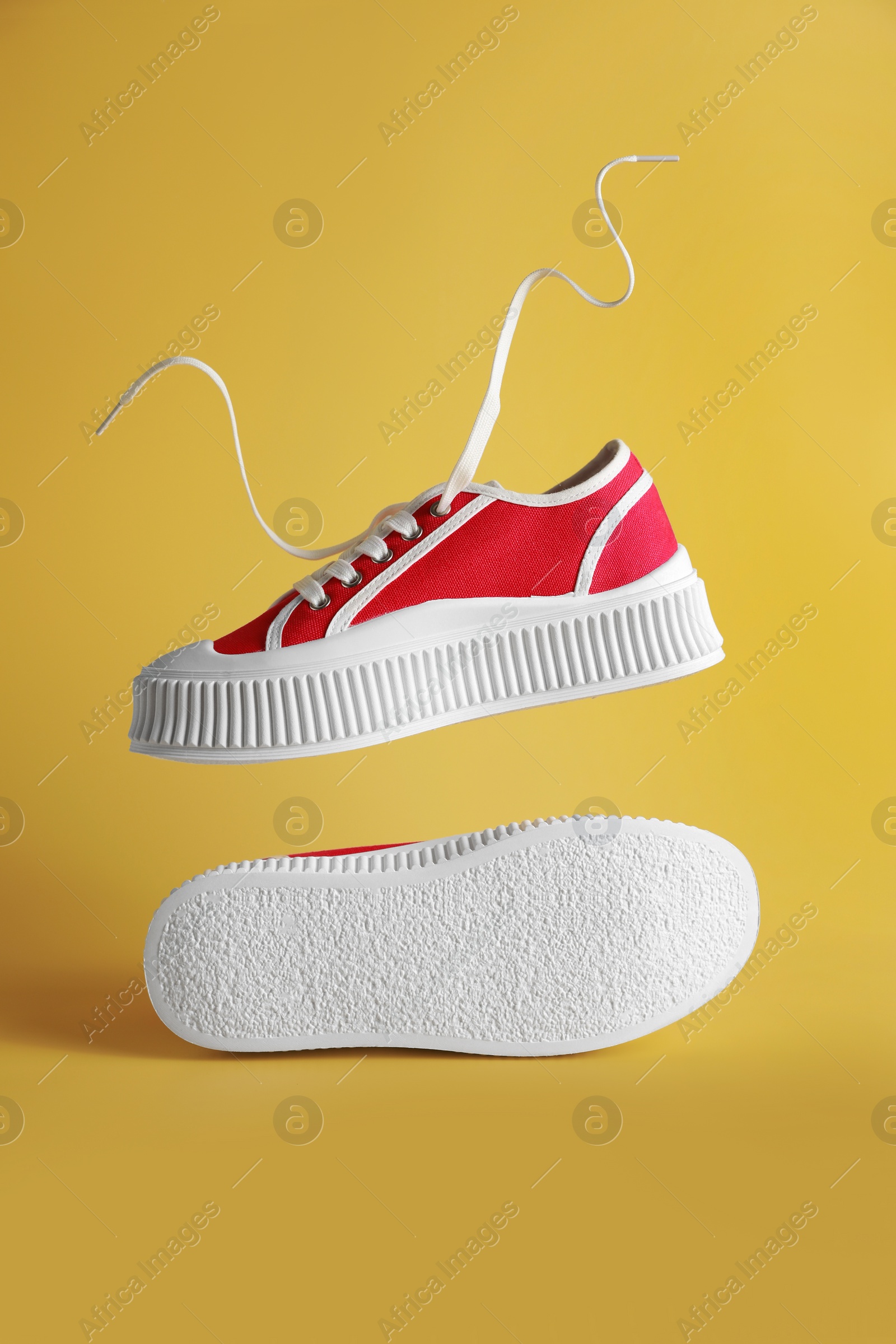 Photo of Pair of red classic old school sneakers on yellow background