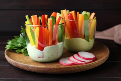 Photo of Fresh raw vegetable sticks with sauce on wooden table