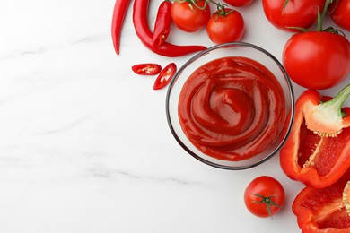 Bowl of tasty ketchup, tomatoes and peppers on white marble table, flat lay. Space for text