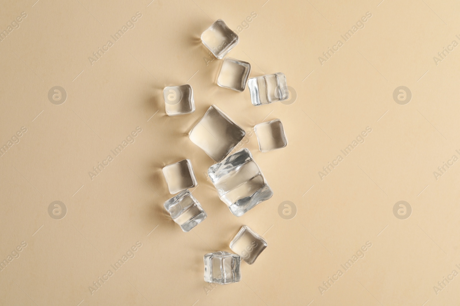 Photo of Crystal clear ice cubes on beige background, flat lay