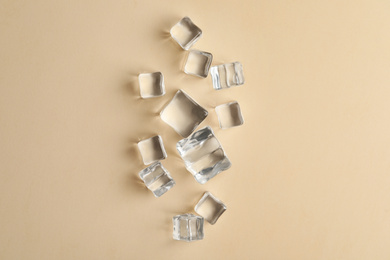 Photo of Crystal clear ice cubes on beige background, flat lay