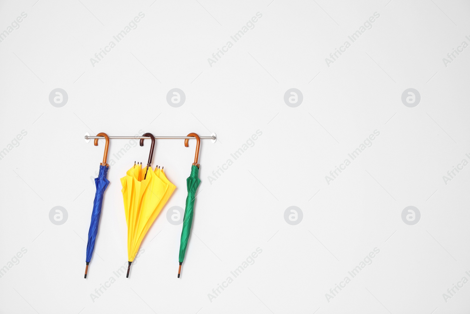 Photo of Beautiful bright umbrellas hanging on wall with space for design