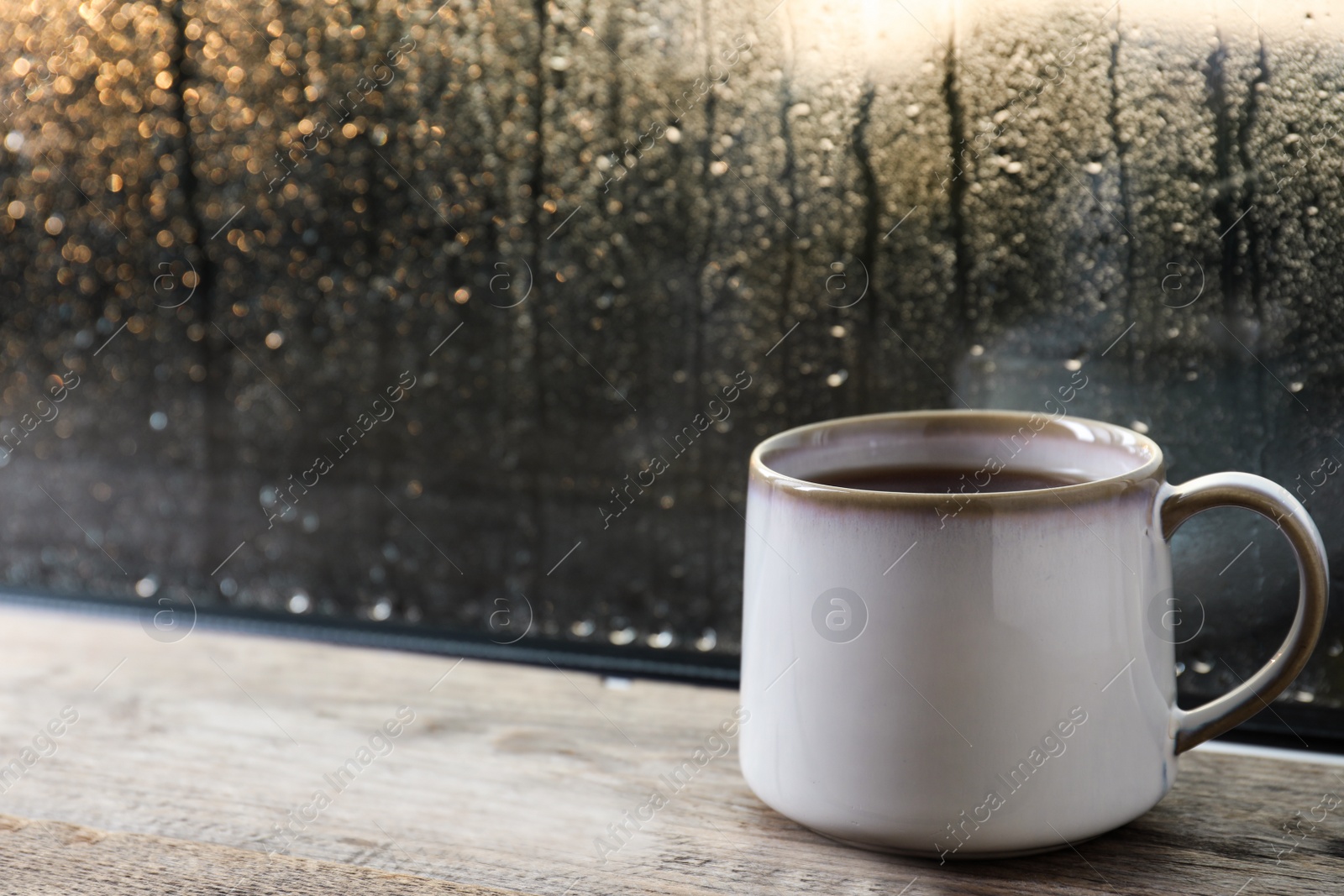 Photo of Cup of hot tea on wooden window sill. space for text. Rainy weather