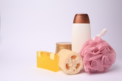 Pink shower puff, loofah sponge and cosmetic products on white background