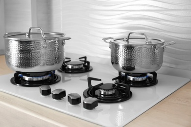 Shiny steel saucepans on modern gas stove