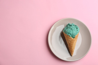 Photo of Plate with delicious spirulina ice cream cone on color background, top view. Space for text