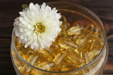 Glass medical bottle with yellow capsules and white flower, closeup