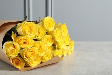 Photo of Beautiful bouquet of yellow roses on light grey table, space for text