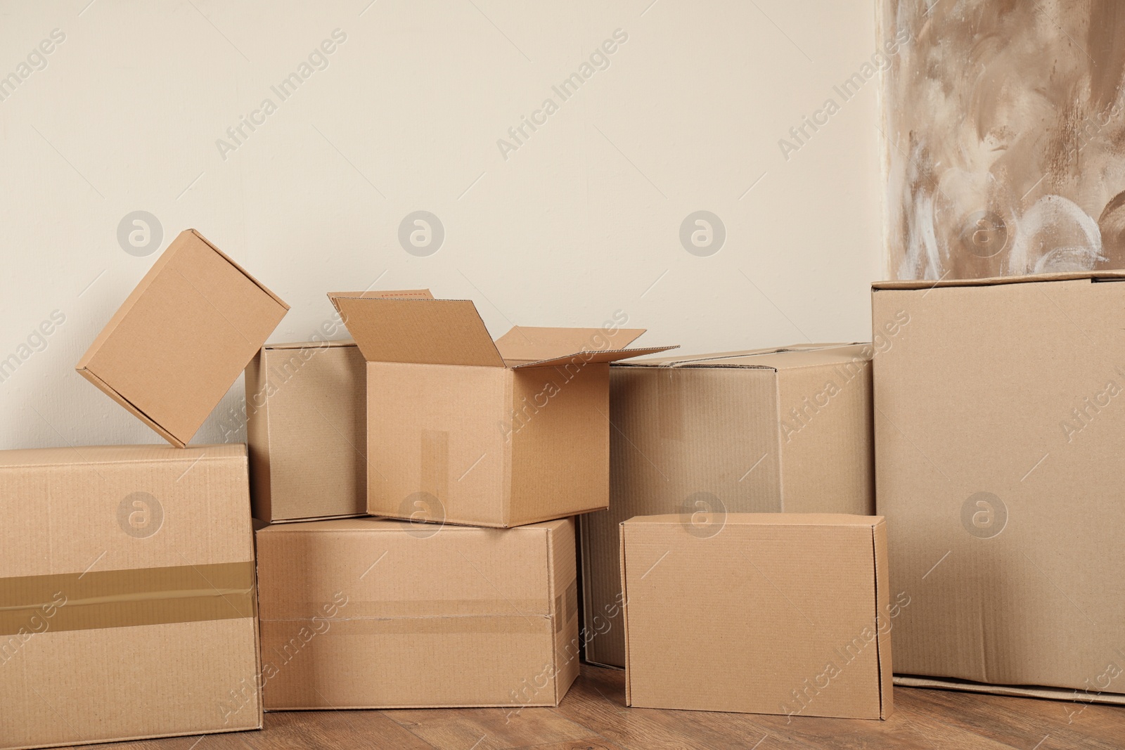 Photo of Pile of cardboard boxes near light wall indoors