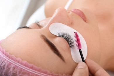 Photo of Young woman undergoing eyelash extensions procedure, closeup