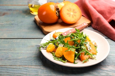Photo of Delicious persimmon salad served on light blue wooden table