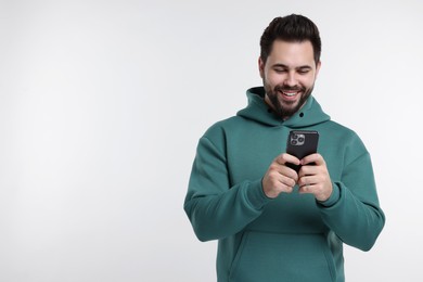 Happy young man using smartphone on white background, space for text