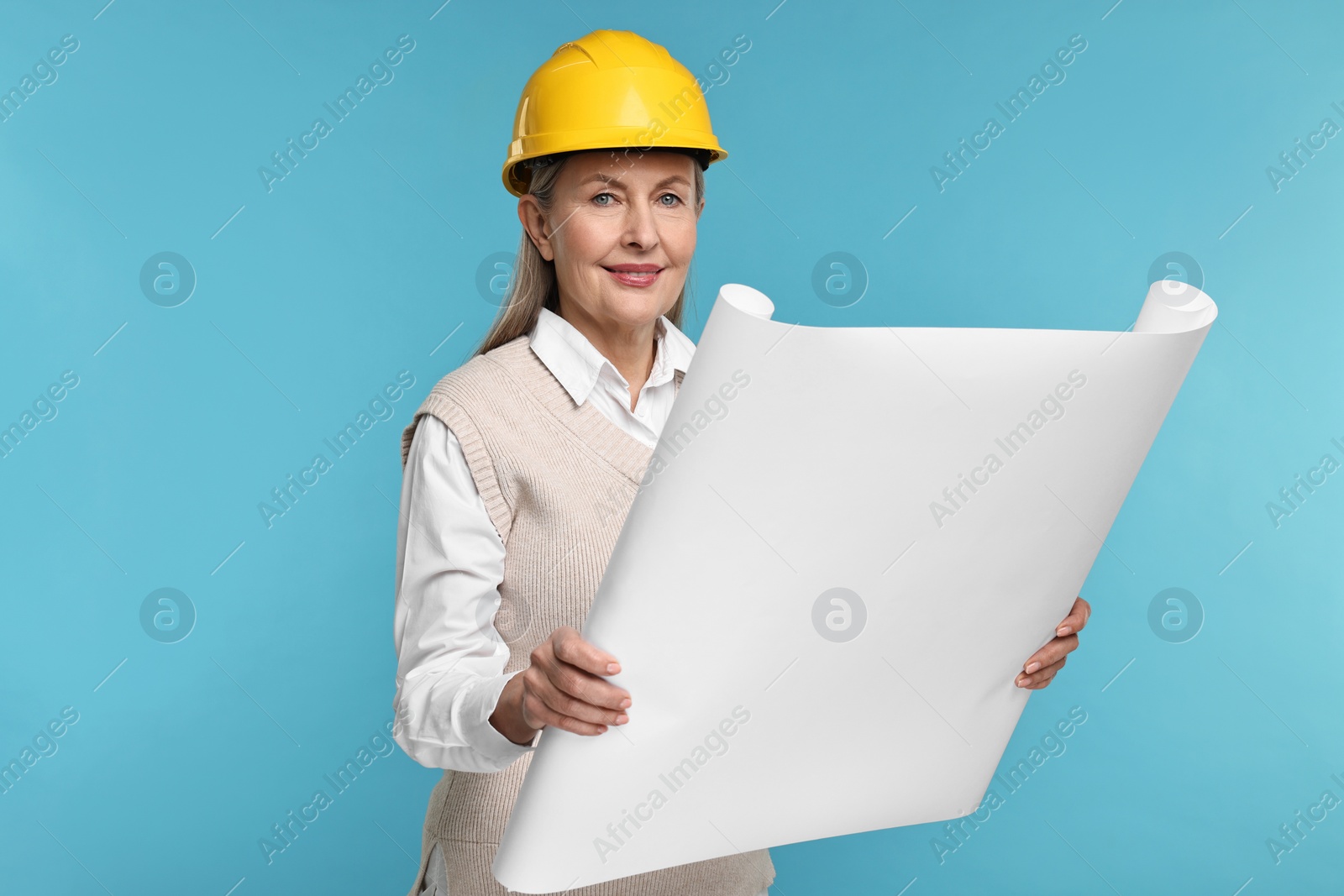 Photo of Architect in hard hat with draft on light blue background