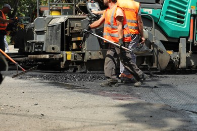 Photo of MYKOLAIV, UKRAINE - AUGUST 04, 2021: Workers with road repair machinery laying new asphalt