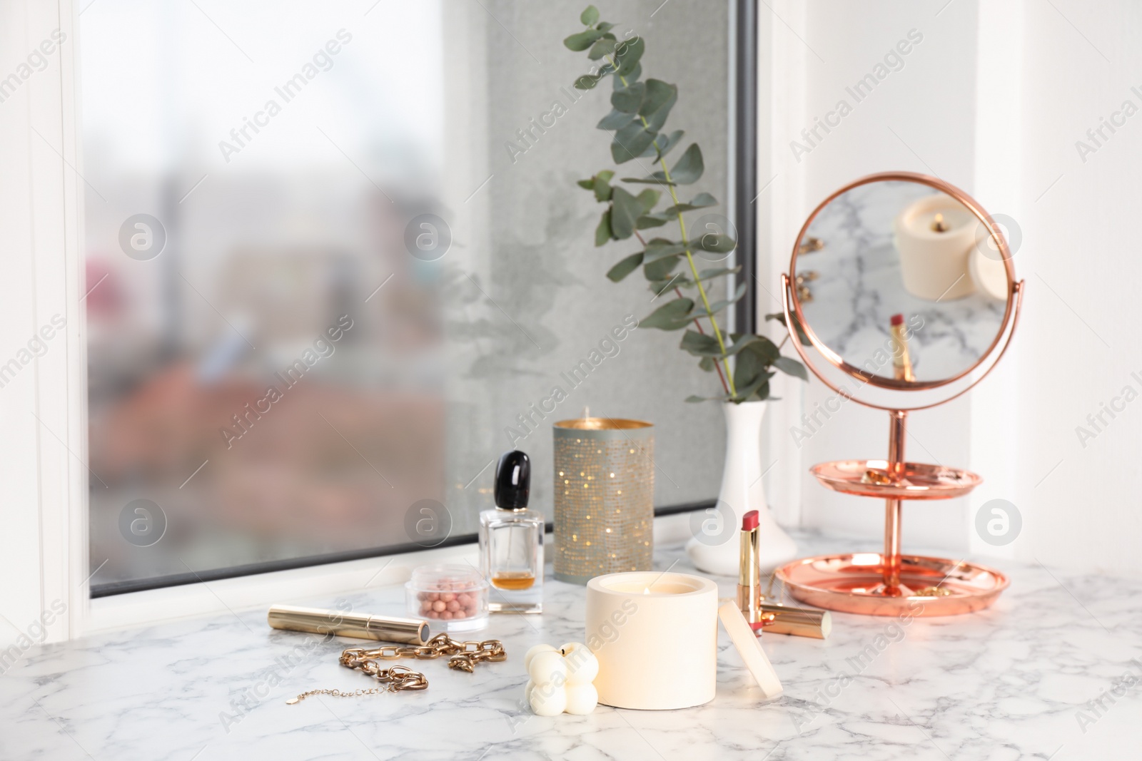 Photo of Burning soy candles, cosmetics and stylish accessories on white window sill indoors