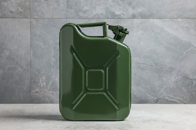 New khaki metal canister on floor near light grey wall