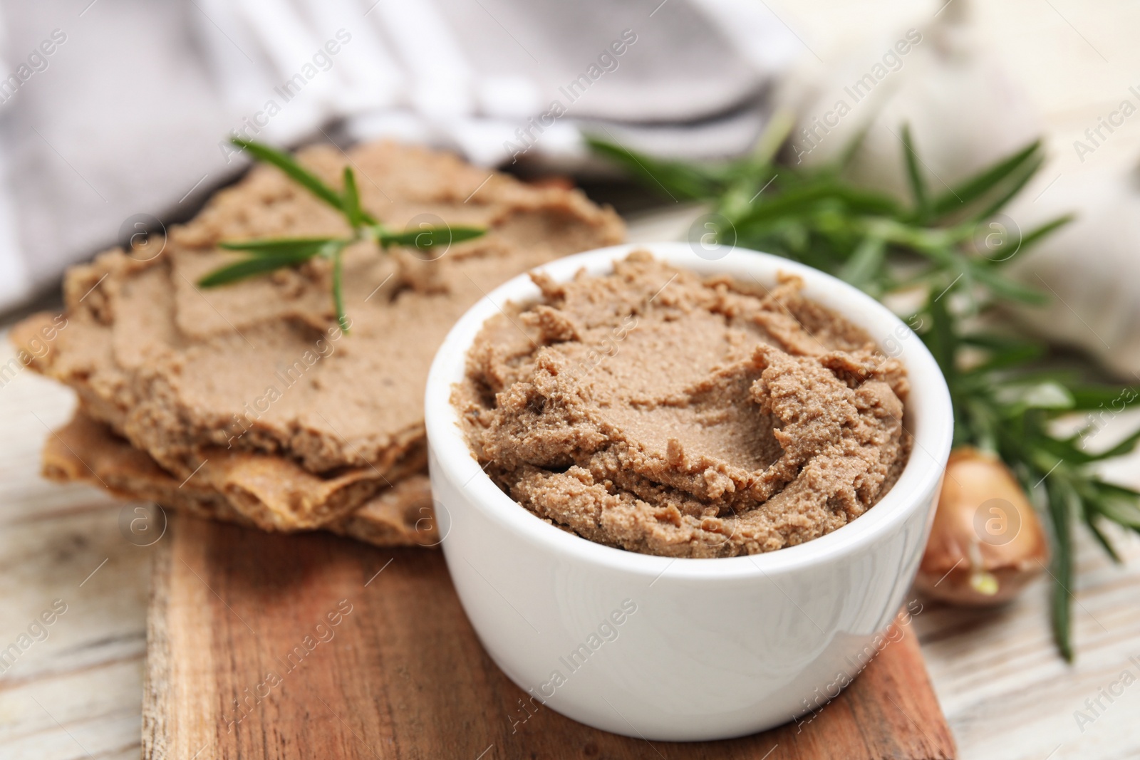 Photo of Delicious meat pate, crispy crackers and rosemary on white wooden table, closeup