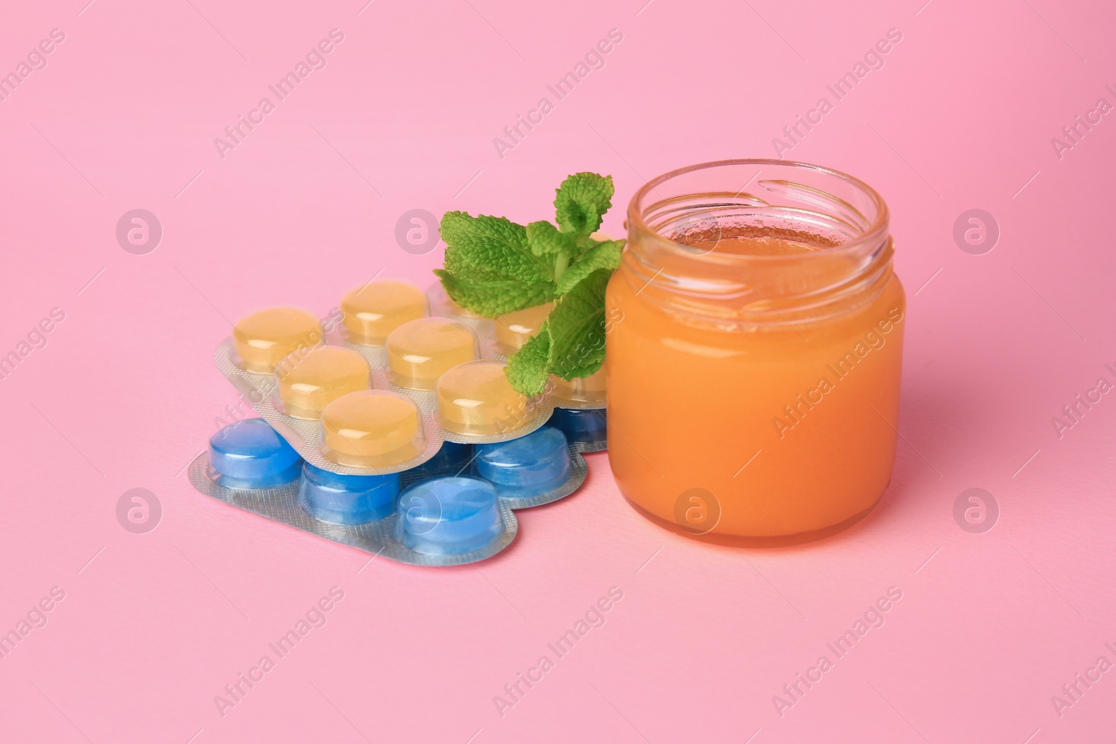 Photo of Blisters with cough drops, honey and mint on pink background