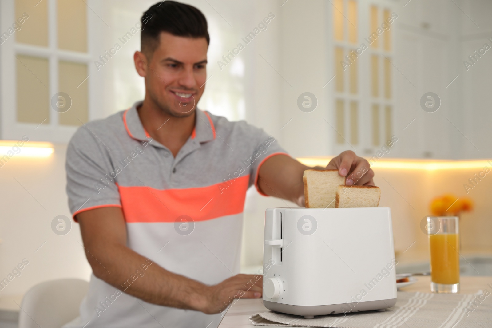 Photo of Man using toaster at table in kitchen