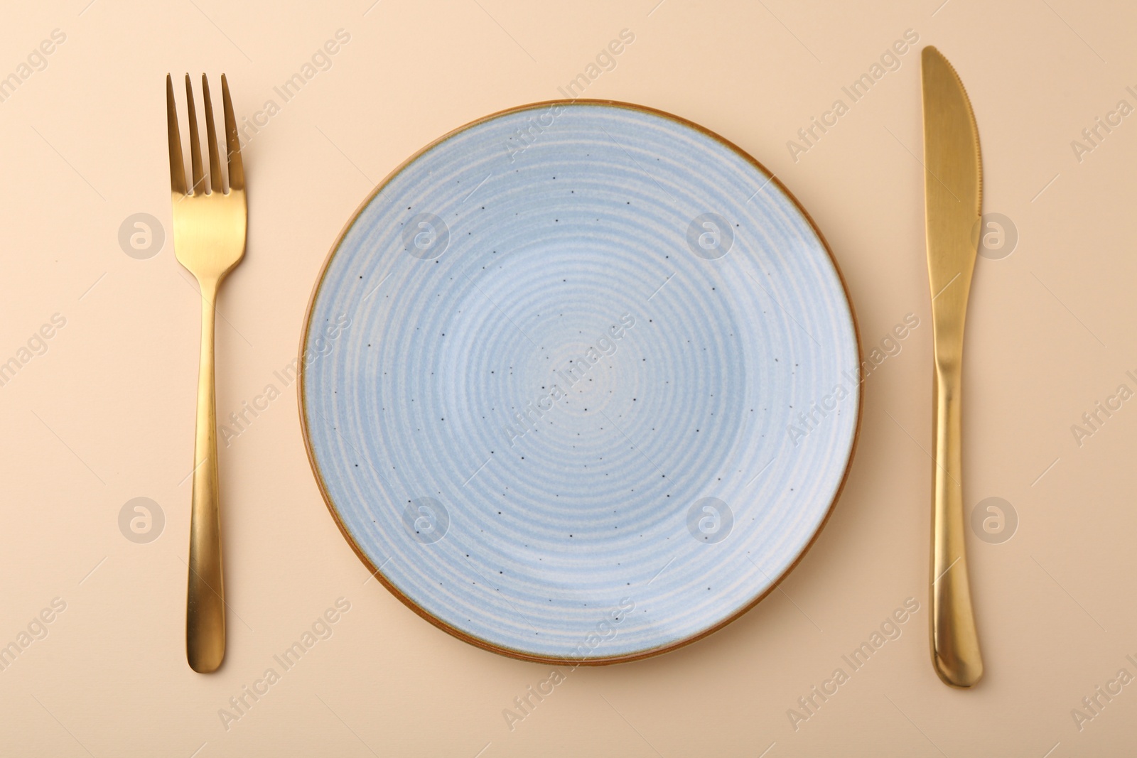 Photo of Setting with stylish cutlery on beige table, top view