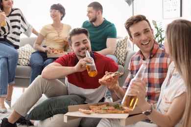 Young people having fun party with delicious pizza indoors