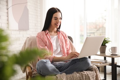 Photo of Beautiful young woman using laptop at home