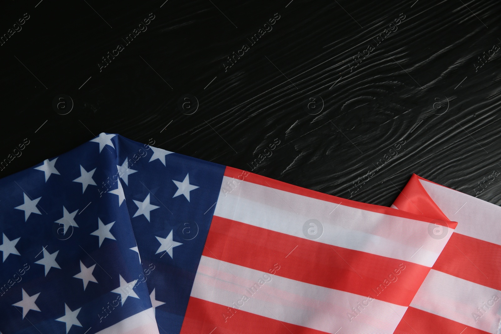 Photo of Flag of USA on black wooden table, top view. Space for text