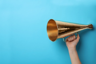 Woman holding retro megaphone on color background