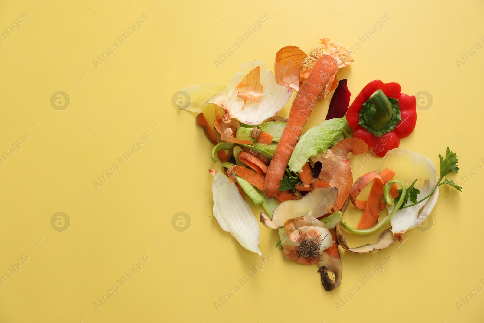 Photo of Peels of fresh vegetables on yellow background, flat lay. Space for text