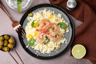 Photo of Tasty couscous with shrimps, bell pepper and basil served on brown textured table, flat lay