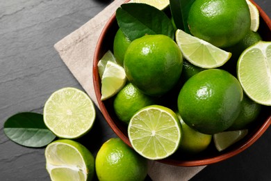 Fresh ripe limes in bowl on black table, top view