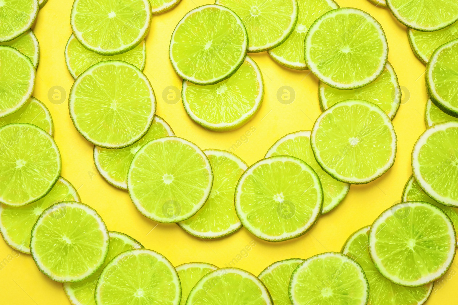 Photo of Juicy fresh lime slices on yellow background, flat lay