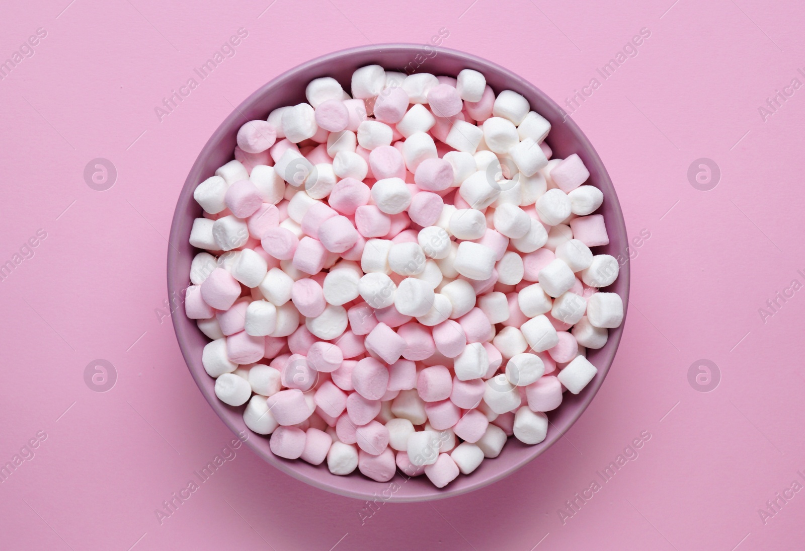 Photo of Bowl with delicious marshmallows on pink background, top view