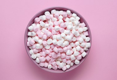 Bowl with delicious marshmallows on pink background, top view