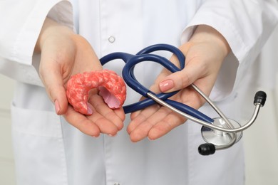 Photo of Endocrinologist holding stethoscope and model of thyroid gland, closeup