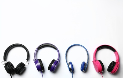 Many stylish headphones on white background, top view