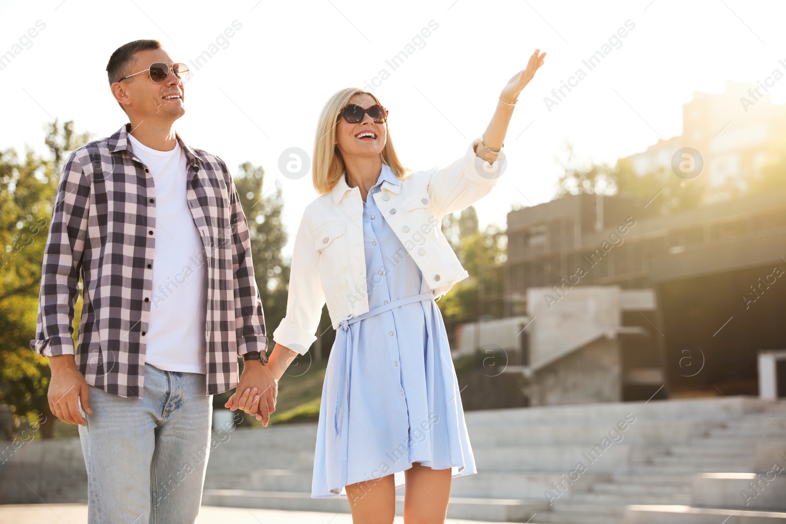 Photo of Happy couple walking along city street on summer day