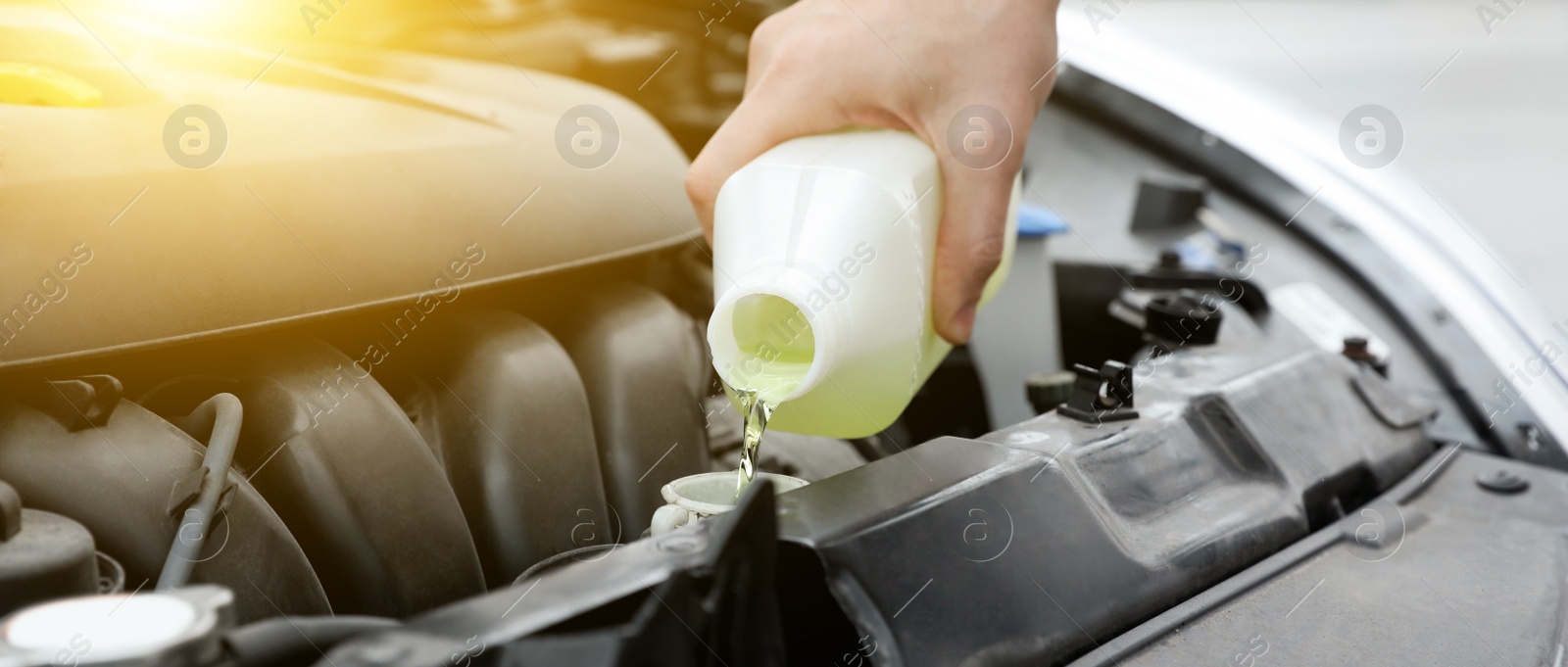 Image of Man filling car radiator with antifreeze outdoors, closeup