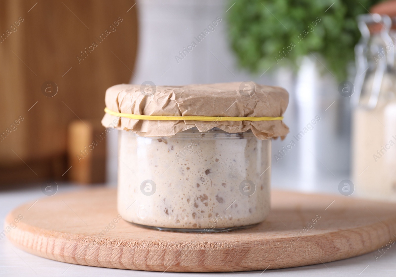 Photo of Sourdough starter in glass jar on table, closeup