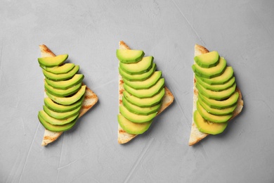 Photo of Tasty toasts with avocado on light grey table, flat lay